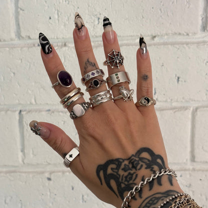 Hand with multiple rings and bracelets against a white brick wall background